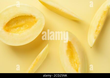 Half and some slices of yellow ripe honeydew melon over yellow background. Vegetarian, raw food diet and healthy eating concept. Sweet fruits, berries Stock Photo