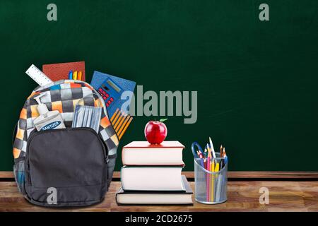 Education back-to-school concept in the new normal classroom setting showing backpack stuffed with stationery, hand sanitizer and face mask on table w Stock Photo