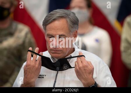 Austin, TX USA August 25, 2020: Texas Gov. Greg Abbott removes his face mask before briefing the media on the state's preparations for Hurricane Laura, scheduled to make landfall in coastal east Texas and southwest Louisiana on Thursday. Abbott mobilized hundreds of state resources as Texans remember the extreme damage done by Hurricane Harvey in 2017. Emergency response officials stand behind Abbott wearing face masks. Credit: Bob Daemmrich/Alamy Live News Stock Photo