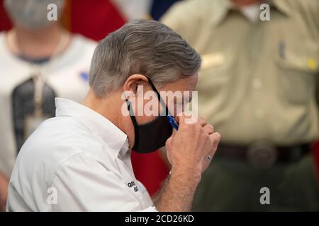 Austin, TX USA August 25, 2020: Texas Gov. Greg Abbott removes his face mask before briefing the media on the state's preparations for Hurricane Laura, scheduled to make landfall in coastal east Texas and southwest Louisiana on Thursday. Abbott mobilized hundreds of state resources as Texans remember the extreme damage done by Hurricane Harvey in 2017. Emergency response officials stand behind Abbott wearing face masks. Credit: Bob Daemmrich/Alamy Live News Stock Photo