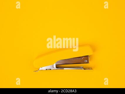 Yellow stapler on yellow background. Top view. Copy, empty space for text. Minimalistic concept Stock Photo