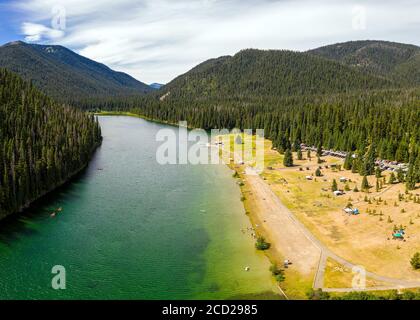 Aerial photo of Lightning Lake and its beach while people are enjoying summer activities like canoeing, kayaking and sunbathing at the lake shore, in Stock Photo