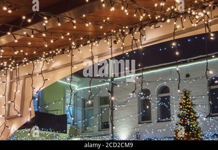 Christmas decoration of buildings, garlands with light bulbs on the facade and roof of the street market against the dark night sky, winter holiday Stock Photo