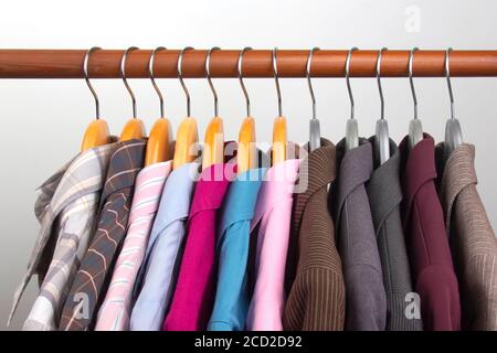 Different women's office classic jackets and shirts hang on a hanger for storing clothes. The choice of style of fashionable clothes Stock Photo