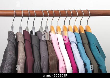 Different women's office classic jackets and shirts hang on a hanger for storing clothes. The choice of style of fashionable clothes Stock Photo
