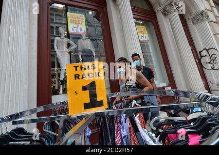 New York City, USA. 25th Aug, 2020. A couple shop at a sale rack set up outsede a “going out of business” store along lower Broadway in New York, NY, August 25, 2020. Despite billions of dollars in economic stimulous offered by the Federal Government, emptied or shuttered stores throughout New York City are a testament to the continued economic impact of the COVID-19 pandemic, with a predicted difficult recovery as New York City's struggles with a predicted $9billion debt. (Anthony Behar/Sipa USA) Credit: Sipa USA/Alamy Live News Stock Photo