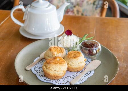 Enjoying Tea and crumpets or scones with jam and creme during High Tea Stock Photo