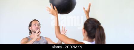 Couple friends training together at gym banner. Cross training class at fitness centre, two friends working out throwing medicine ball at each other. Stock Photo