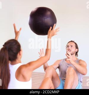 Couple training together at gym. Cross training class at fitness centre, two friends working out throwing medicine ball at each other, sports buddy. Stock Photo