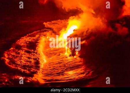 Lava flow pouring into Hawaii ocean at night. Lava falling in ocean waves in Hawaii from Hawaiian Kilauea volcano at night. Molten lava washed by the Stock Photo