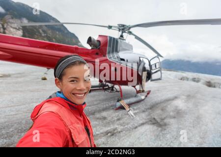 Happy tourist taking selfie picture on helicopter tour excursion. Asian woman cruise passenger on shore activity glacier walk hike in Alaska, USA. Stock Photo