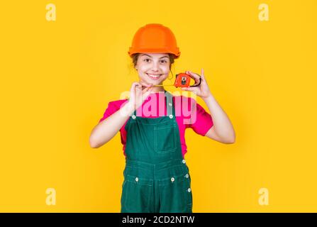 This is my place. kid builder wear helmet. teen girl in hard hat and uniform. building and construction. concept of repair. Little girl using a measuring tape. engineer. happy child hold tape measure. Stock Photo