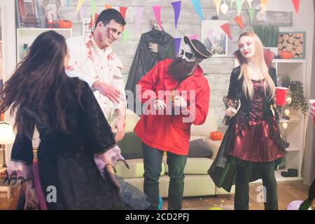 Man dressed up like scary zombie with blood on his face at halloween celebration with his friends. Stock Photo