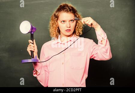 Creativity and inspiration. Teacher hold table lamp in hand chalkboard background. Knowledge day. Light up process of studying. Insight and idea. Educational idea. Woman work on bright shiny idea. Stock Photo