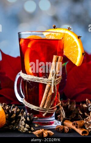 Christmas drink. Glasses of hot mulled wine with oranges, anise and cinnamon next to the red poinsettia flower. Stock Photo