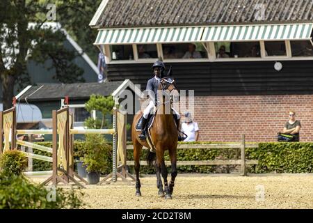 HOGE HEXEL, NETHERLANDS - Aug 15, 2020: In preparation for obstacle course jumping young horseback rider on a large stallion horse Stock Photo