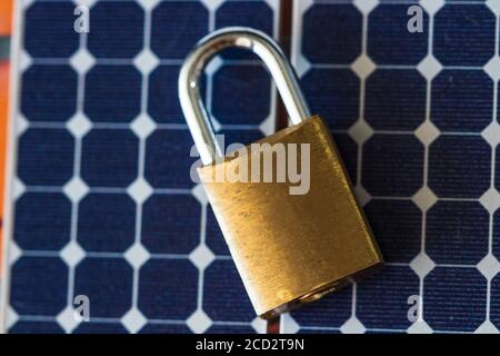 Padlock with key on photovoltaic solar panel on black background. Stock Photo