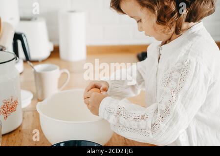 Little girl preparing dough for pancakes at the kitchen. Concept of food preparation, selective focus, close up on details. Casual lifestyle photo ser