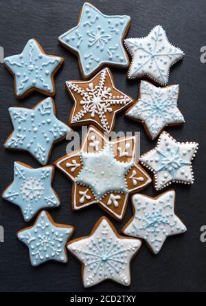 Homemade gingersnaps coverd icing on the dark plate: snowflakes and stars; delicious cookies with Christmas shapes Stock Photo