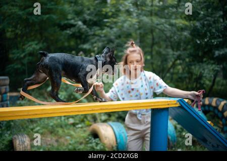 girl play with cute little frenchie bulldog puppy in park at summer day Stock Photo