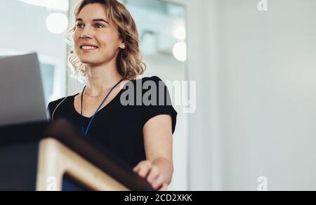 Female entrepreneur standing at podium in conference. Woman business professional giving presentation in a conference. Stock Photo
