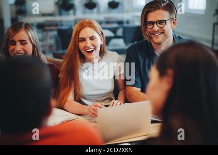 Group of young people smiling during group study in the classroom. Students chatting while studying together in high school. Stock Photo