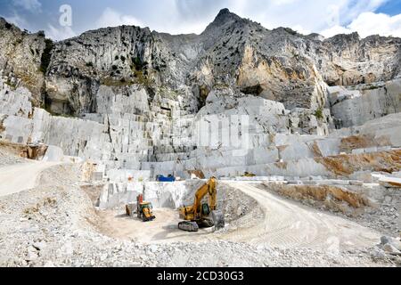 Landscape view of an open cast marble quarry in Carrara, Tuscany, Italy showing the heavy duty equipment and rock face Stock Photo