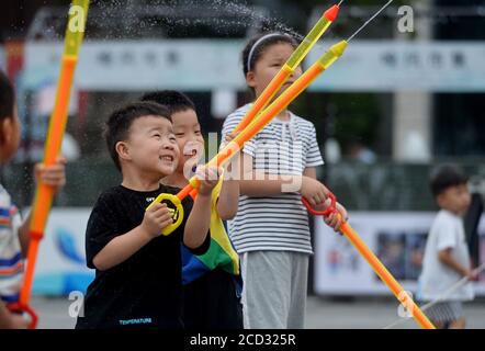 Children play water around the fountain to spare leisure time in summer as Xiaoshu, 11th solar term of the year is coming and the weather is getting h Stock Photo