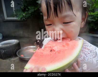 Kids play around the well and eat watermelon which is cooled by water from the well to spare leisure time in summer as Xiaoshu, 11th solar term of the Stock Photo