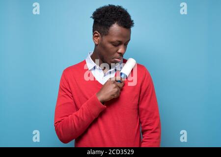 African man holding a white sticky brush for cleaning clothes from dust Stock Photo