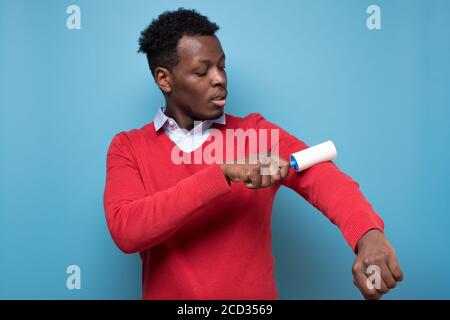 African man holding a white sticky brush for cleaning clothes from dust Stock Photo