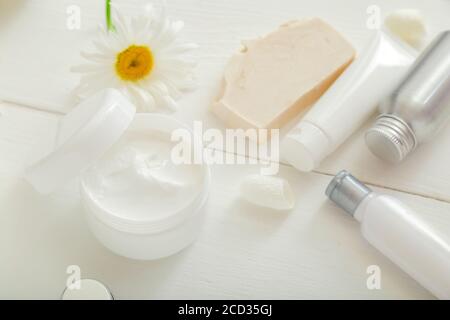 Moisturizer skin cream in white jar with chamomile flowers set white skincare products soap in tubes and bottles. Mockup white plastic jar for Stock Photo