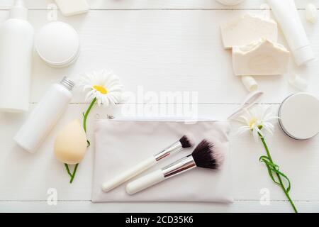Set white cosmetic products on wooden table with flowers as frame. Beauty makeup brushes skincare hair treatment cosmetic moisturizer skin cream soap Stock Photo