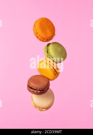 Colored french macarons flying in freeze motion. Concept of flying food isolated on pink background. High resoution image Stock Photo