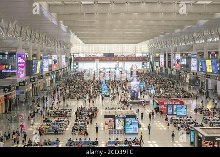 An aerial view of crowd of passengers either sitting or standing in the hall, waiting for trains taking them to different destinations, Shanghai, Chin Stock Photo