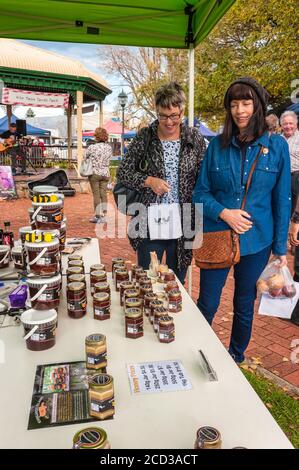 Two friends smiling and sharing a shopping experience as they walk up to the next stall at Victor Harbor Farmers Market in South Australia. Stock Photo