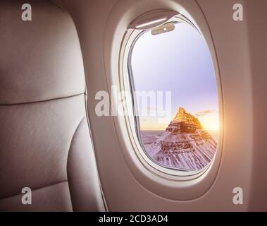 Airplane interior with window view of Kirkjufell mountain, Iceland. Concept of travel and air transportation Stock Photo