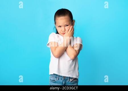 Adorable asian girl touching her cheek at studio Stock Photo