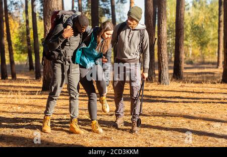 Multiracial guys supporting their female friend with injured anckle Stock Photo