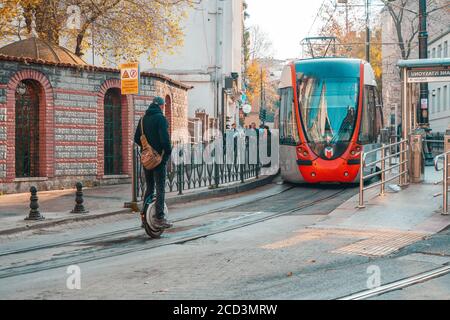 18.12.2019, Istanbul, Turkey. A man rides along the road on a monocycle. A tram rides in the background. Urban transport. Stock Photo