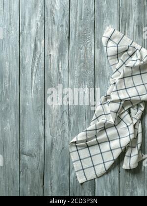 Gray wooden table with linen kitchen towel or textile napkin flat lay. Blue tablecloth on old gray wood tabletop. Copy space for text. Can use as mock up for design. Vertical. Stock Photo