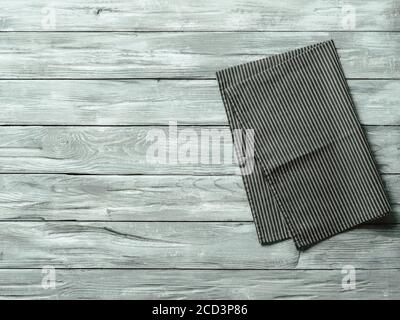 Gray wooden table with balck and white dark linen kitchen towel or textile napkin flat lay. Dark tablecloth on old gray wood tabletop. Copy space for text. Can use as mock up for design. Stock Photo