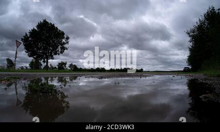 Burgdorf, Germany. 26th Aug, 2020. Deep dark clouds are reflected in a puddle of rain near Burgdorf. The storm 'Kirsten' brought gusty, rainy and generally quite autumnal weather to Lower Saxony and Bremen on Wednesday. Credit: Peter Steffen/dpa/Alamy Live News Stock Photo