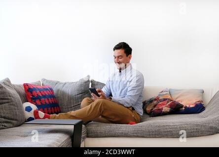 Smiling man typing on smartphone Stock Photo