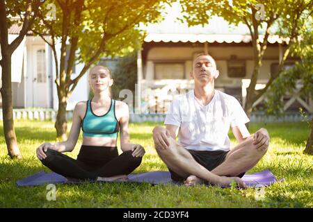 Young couple practicing yoga in the garden. Summer morning Stock Photo