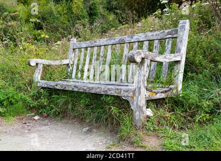 Old rotting wooden public bench with nobody sitting on it. Stock Photo