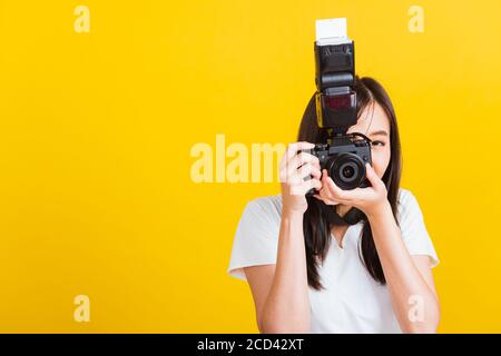 Portrait of happy Asian beautiful young woman photographer smile take picture and looking viewfinder on retro digital mirrorless photo camera ready to Stock Photo