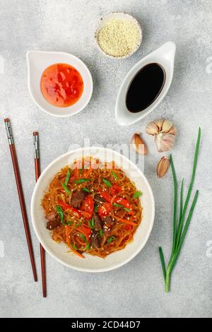 Starch (rice, potatoes, beans) noodles with beef and vegetables - bell peppers, carrots, red and green onions, garlic, sesame seeds, chili and soy sau Stock Photo