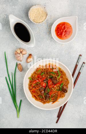 Starch (rice, potatoes, beans) noodles with beef and vegetables - bell peppers, carrots, red and green onions, garlic, sesame seeds, chili and soy sau Stock Photo