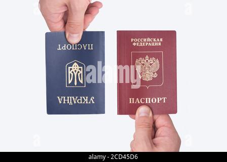 Ukrainian and Russian international passports in the man's hand. White background. Close up Stock Photo